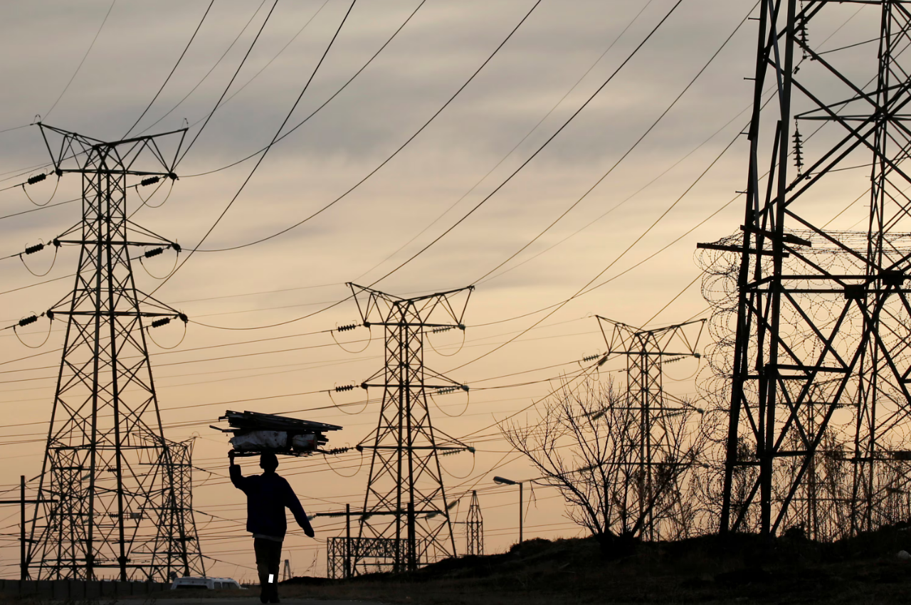 A woman carries fire wood on her head as she walks below state power utility ESKOM's elecricity pylons in Soweto, South Africa, August 8, 2016.